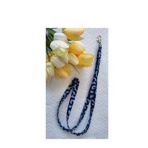 Blue leopard print lanyard with a silver clip on a white background with yellow flowers.