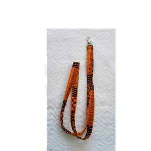 Orange and black patterned lanyard on a textured white background